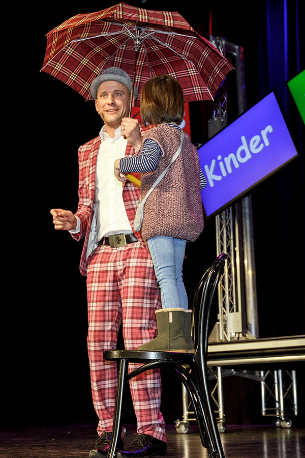 Kinderzauberer Olli zaubert mit Kind auf der Bühne